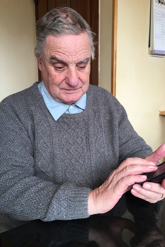Man wearing a great jumper ad blue shirt using a mobile phone.