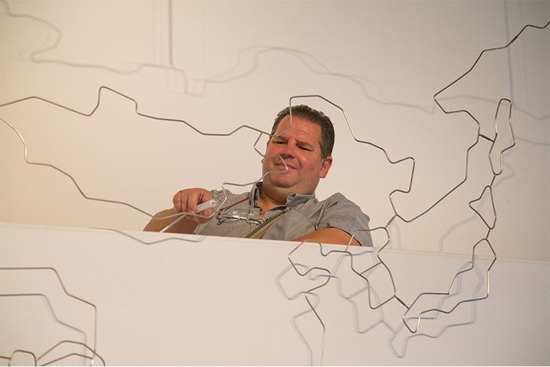 Man concentrating on a large wire puzzle.