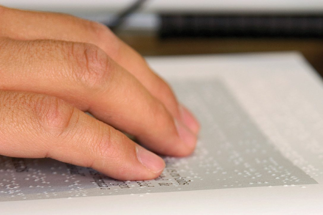 Close up of a hand reading Braille