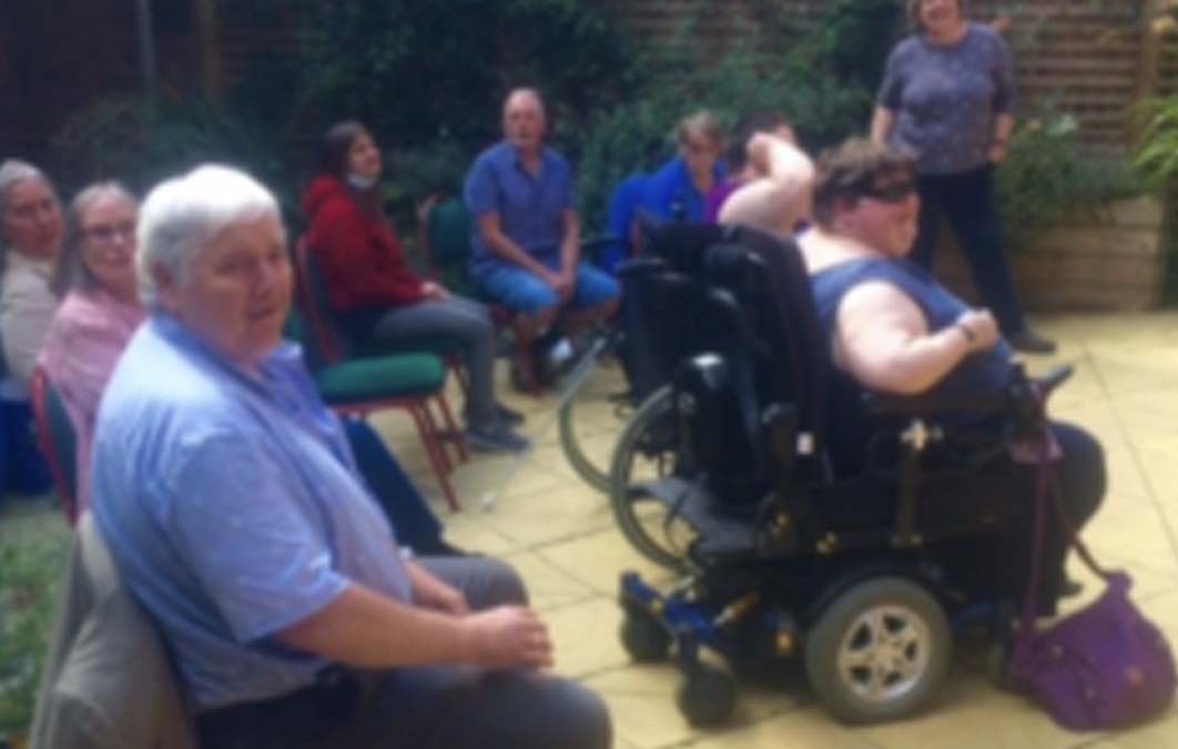 My Sight Notts' Choir seated in a garden practising.