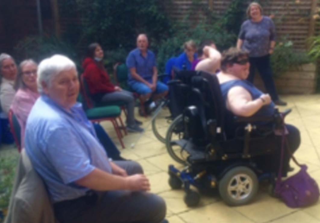 Choir My Sight Notts' Choir seated in a garden practising.