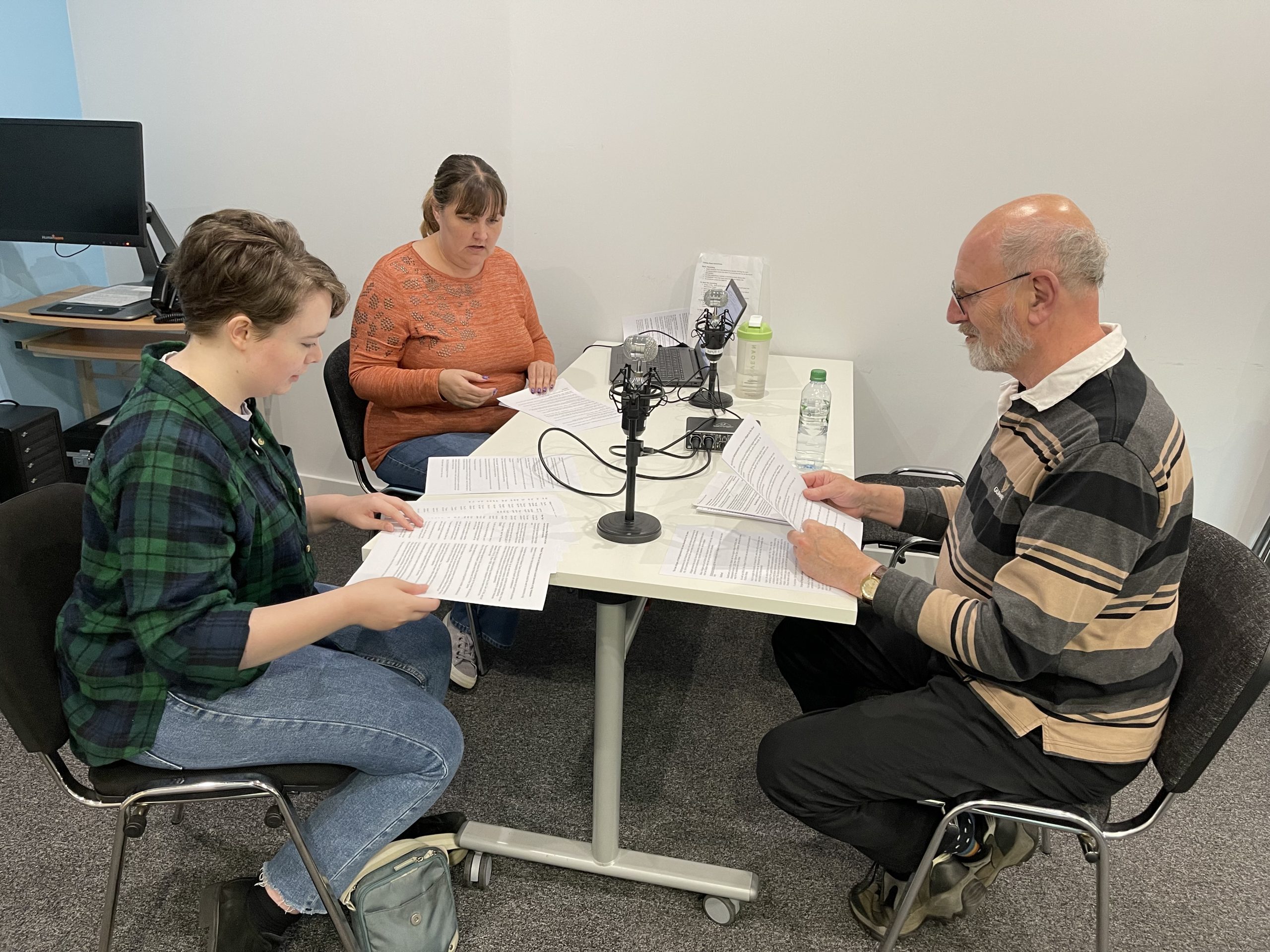 Two women and one mane reading text for Talking News