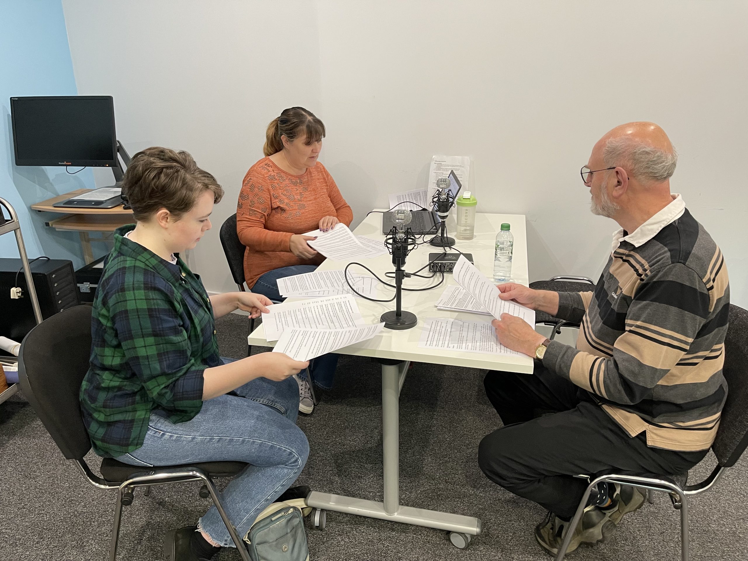 Two women and one mane reading text for Talking News