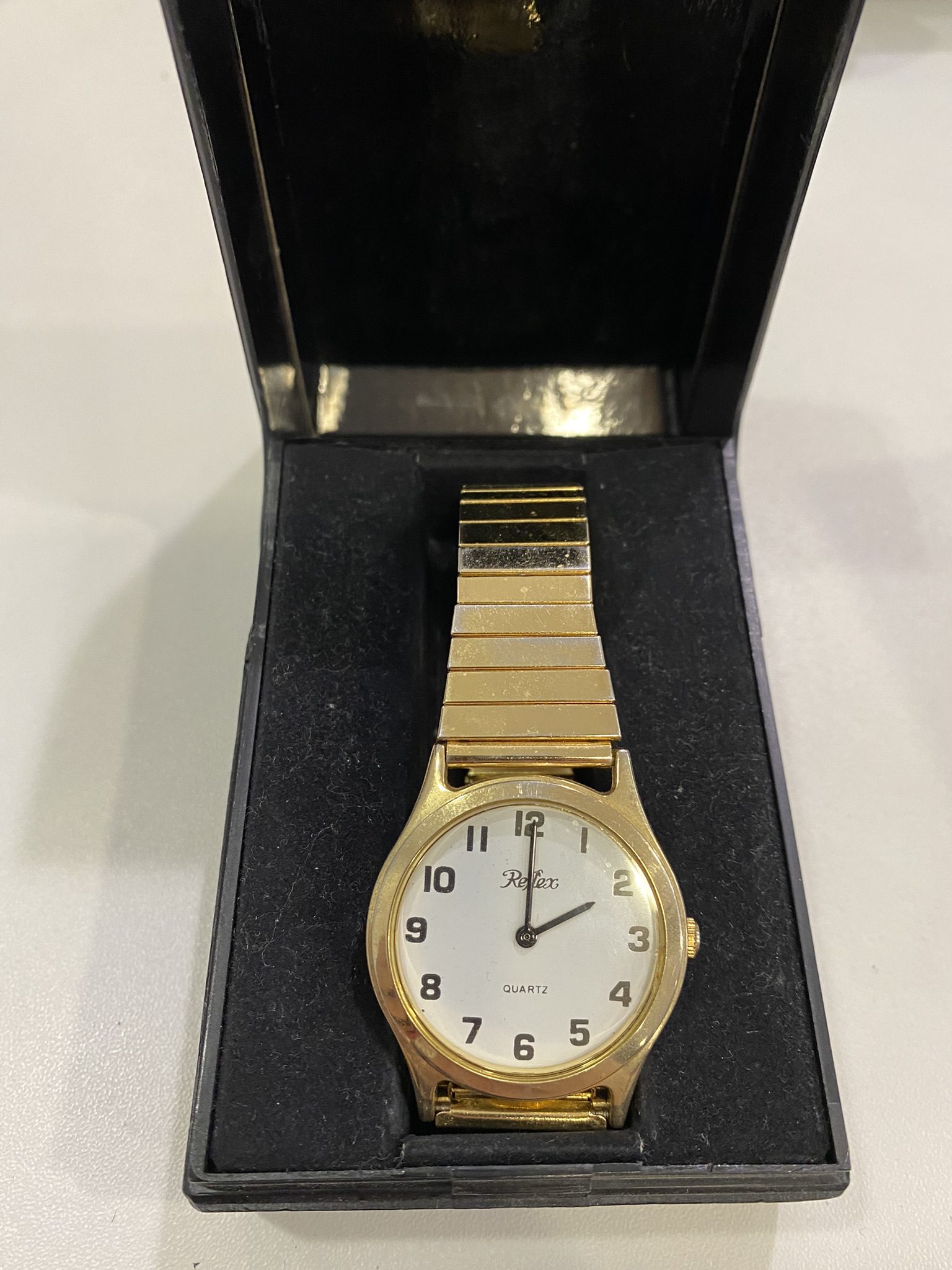 Large text watch with gold strap.