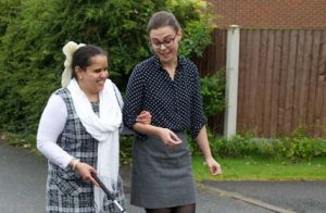 Female volunteer sighted guide assisting a woman with a white cane.