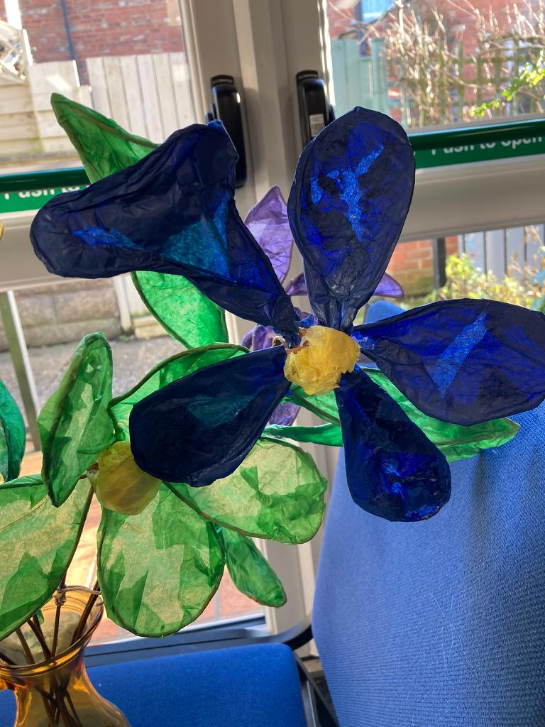 2 paper flowers, one bright blue and two bright green with yellow centres.