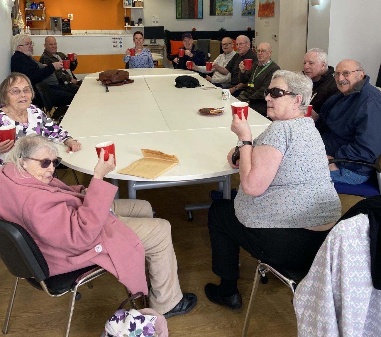 Group of people around a table holding up mugs