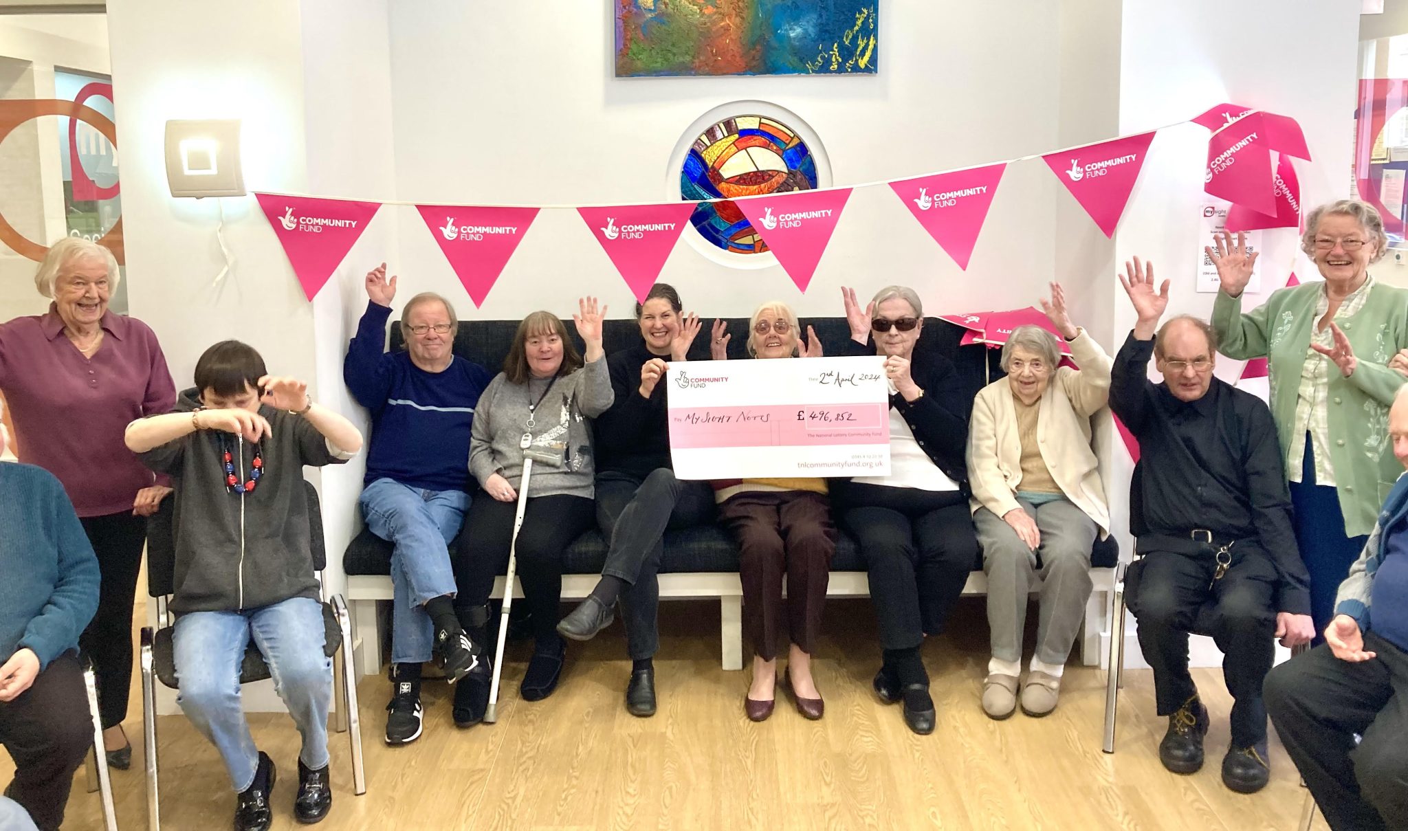 Group of people with hands in the air holding a cheque for £496,252 from the Community Fund