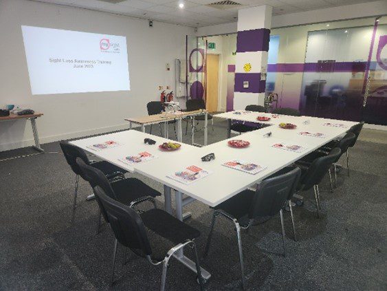 Tables and chairs in a room ready for training with a projector showing information on a wall.