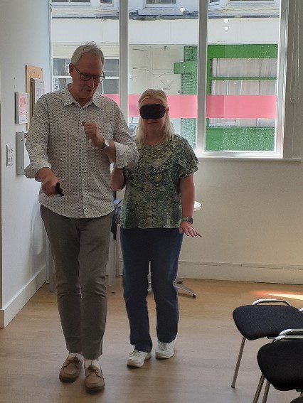 A person guiding another person wearing a blindfold