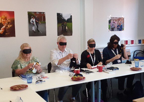 People wearing blindfolds sitting at a desk